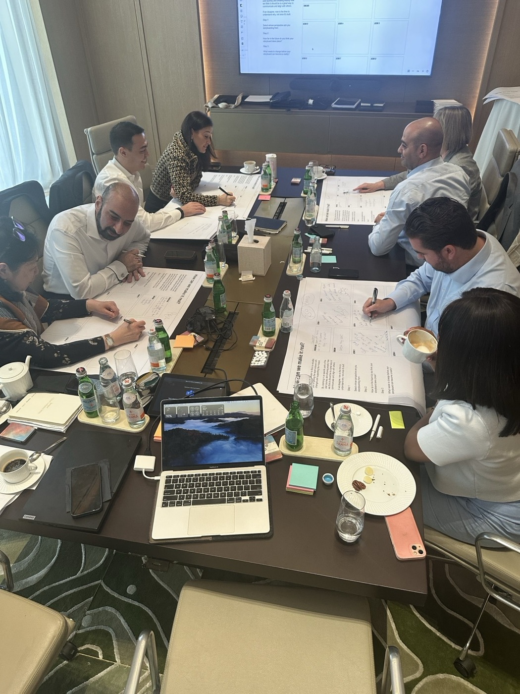 Cross-functional team working through printed material around a boardroom table